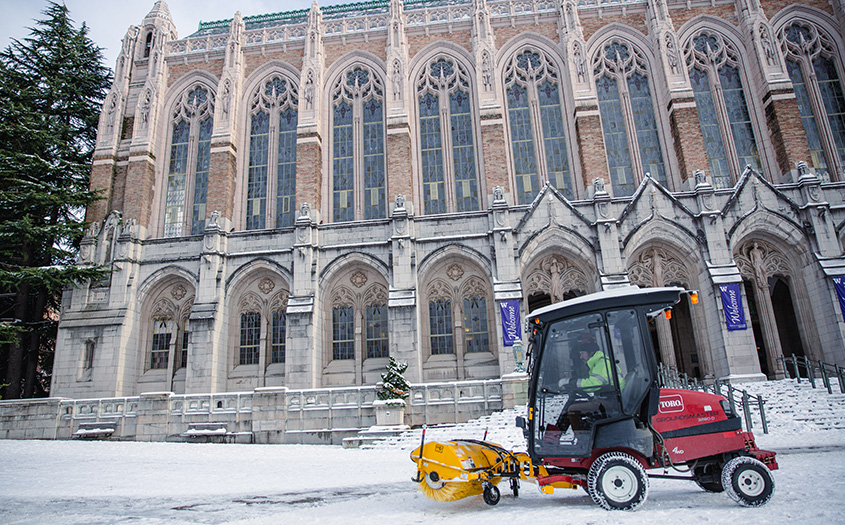 a snow plow clears snow in front of Suzzallo library