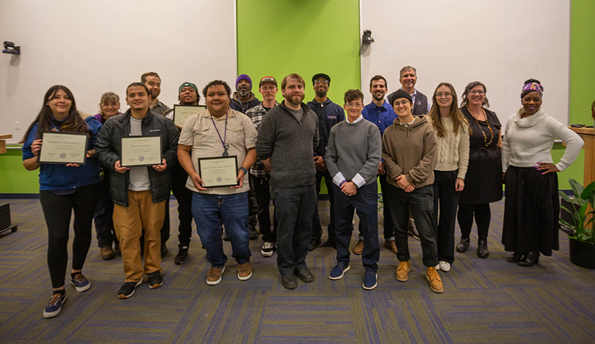 group of people posed together, half of them hold diplomas