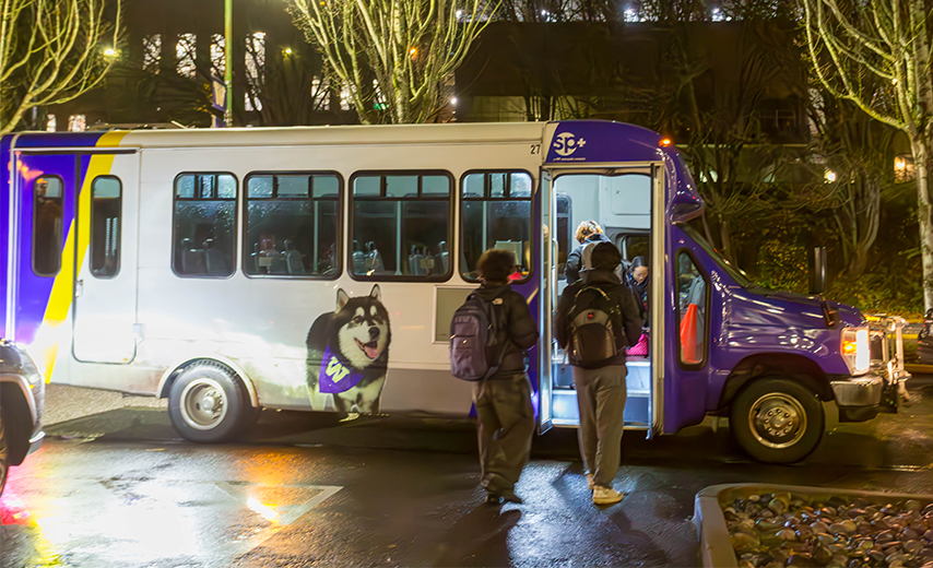 two students get on shuttle with UW colors at night