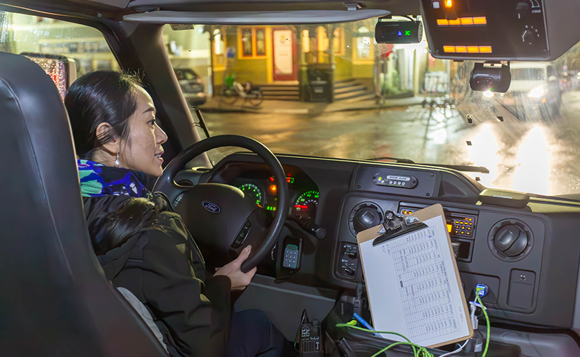 view of woman driving a shuttle from inside the shuttle looking out the front