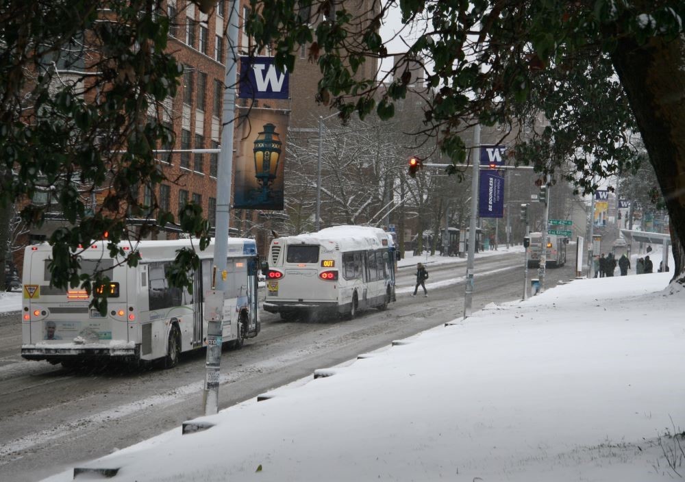Buses driving North on a snowing 15th Avenue