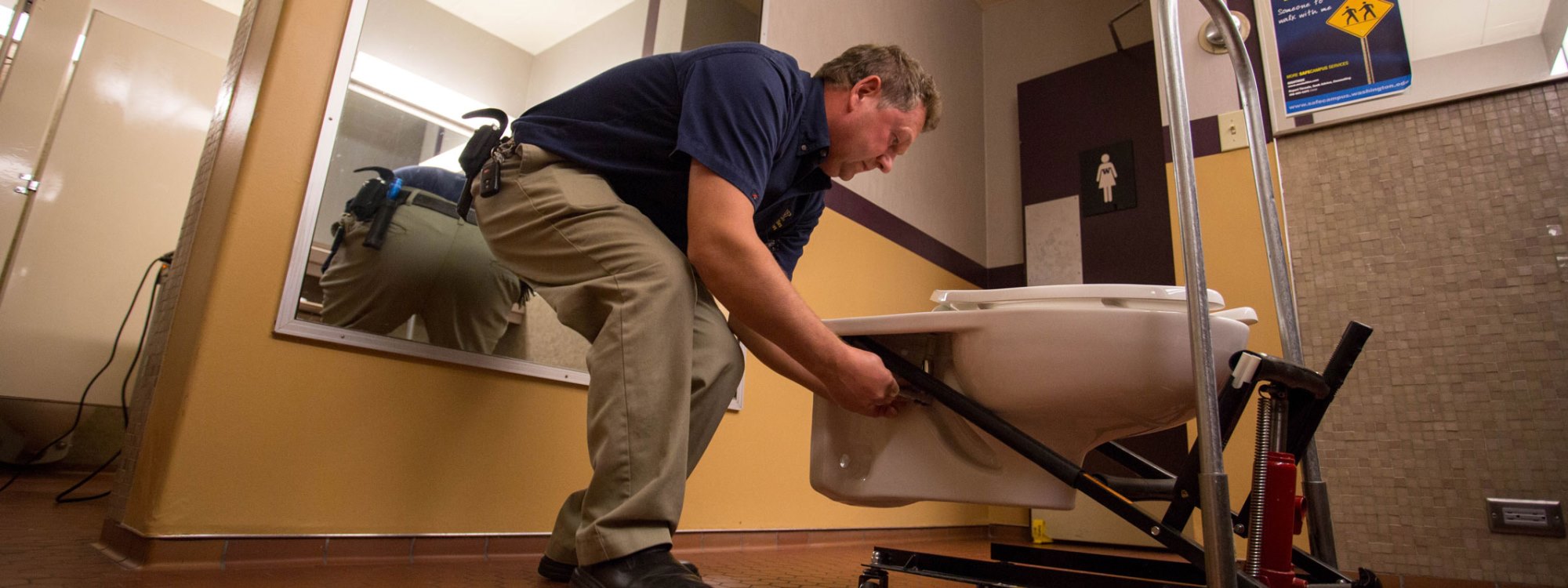Peter Gorokhovskiy, a Facilities operations maintenance specialist from UW Tower, works to replace an older toilet model at the Tower in Seattle, Wash.
