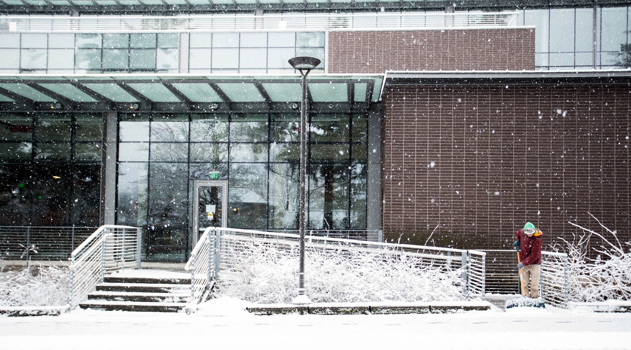 An employee clears a path outside of the Husky Student Union Building (HUB).