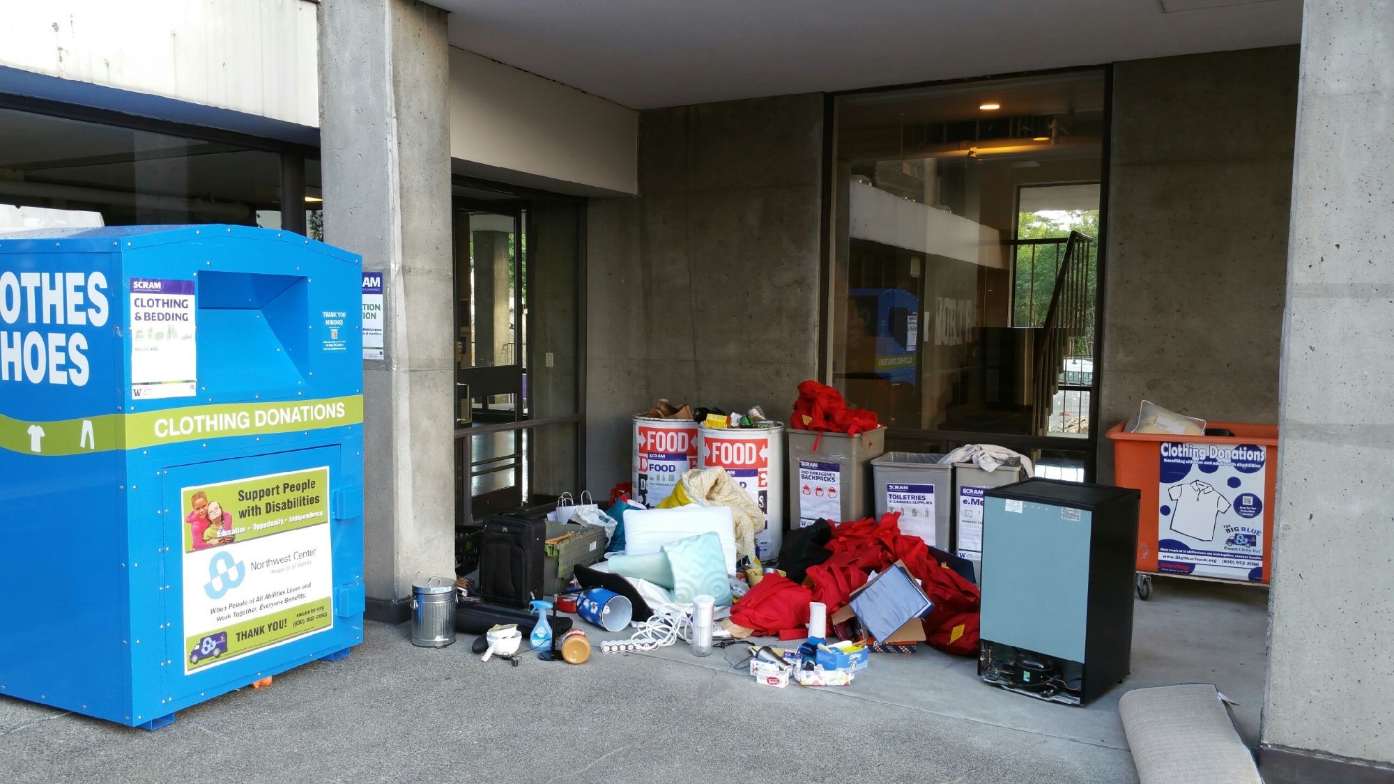 Donation bins filled and surrounded by a variety of donated items.