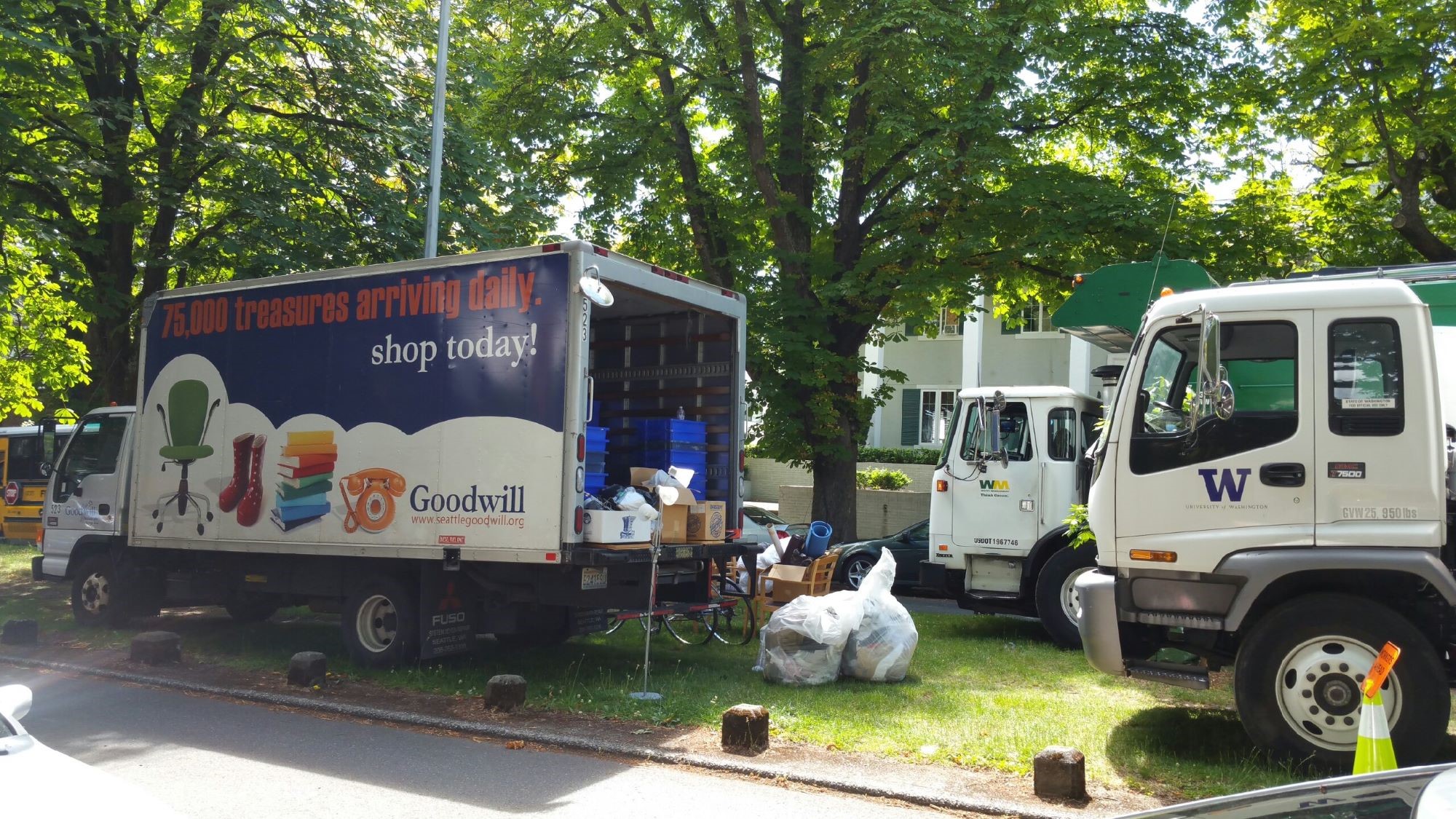 Three trucks parked on Greek Row collect items during Husky Neighborhood Cleanup