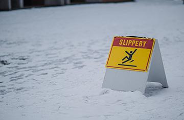 snowy ground with a sign that reads 'slippery'