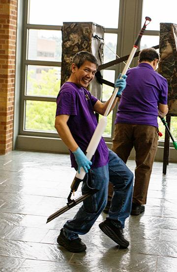 Man holding a mop like a guitar smiling at the camera