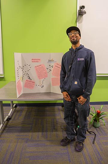 man stands next to a poster board