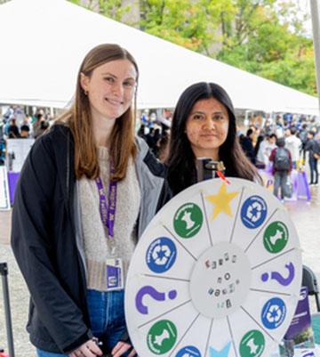 Taylor and Florencia working at a booth with a prize wheel