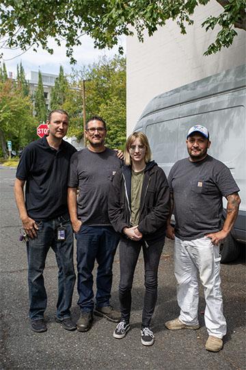 four people standing in a row outside