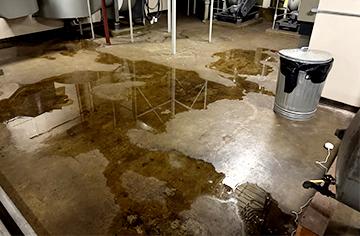 water on cement floor of mechanical room with small sensor to the side