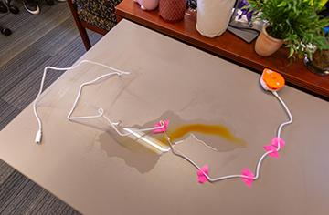 orange device with cord with pink tags on table that has water on it