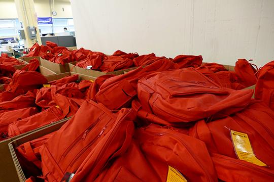 Large boxes filled with red emergency backpack donations