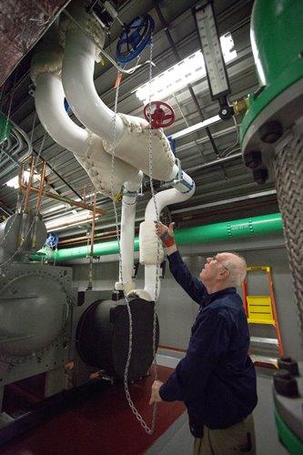 David Record turns on valves before starting up the building’s chiller.