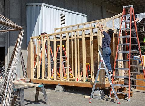 people on ladders building a shed