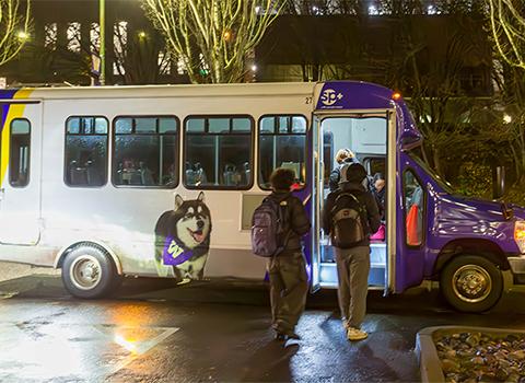 two students get on shuttle with UW colors at night