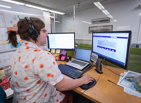 person sits at desk with two screens