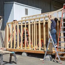 people on ladders building a shed