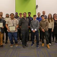 group of people posed together, half of them hold diplomas