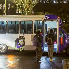 two students get on shuttle with UW colors at night