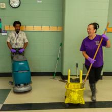 woman smiling as she mops and man with cleaning machine