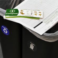 Two public area bins with a stack of compost labels sitting on top.