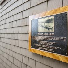 A plaque commemorating UW's crew team on the side of the old canoe house