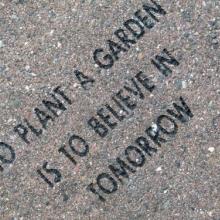 A paving stone engraved with the quote "To plant a garden is to believe in tomorrow."