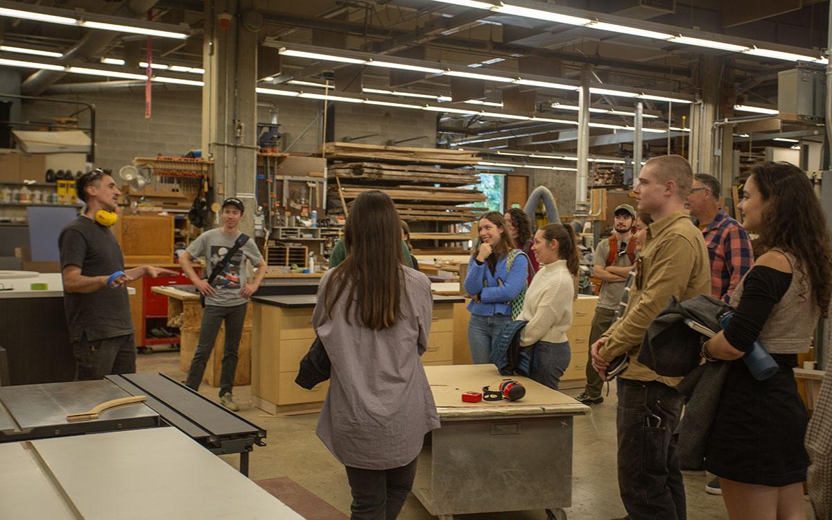 students gathered around a person giving a tour of the UW carpentry shop