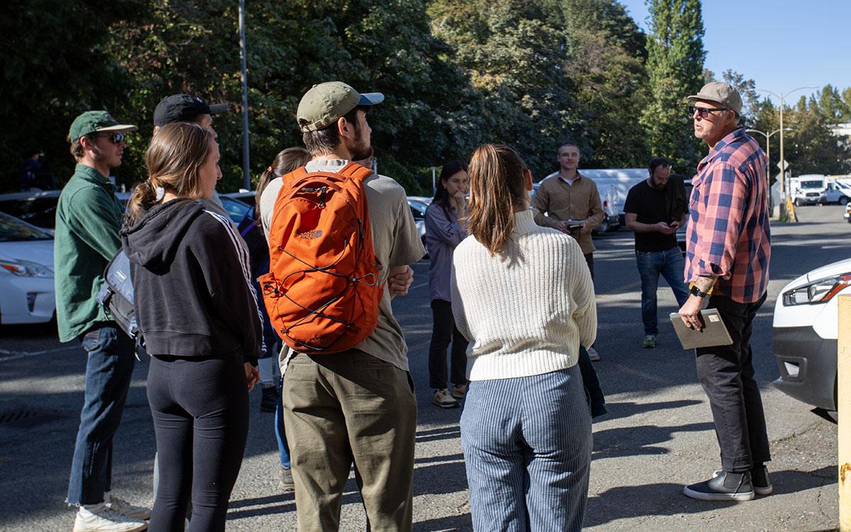 man talking to group of students in parking lot