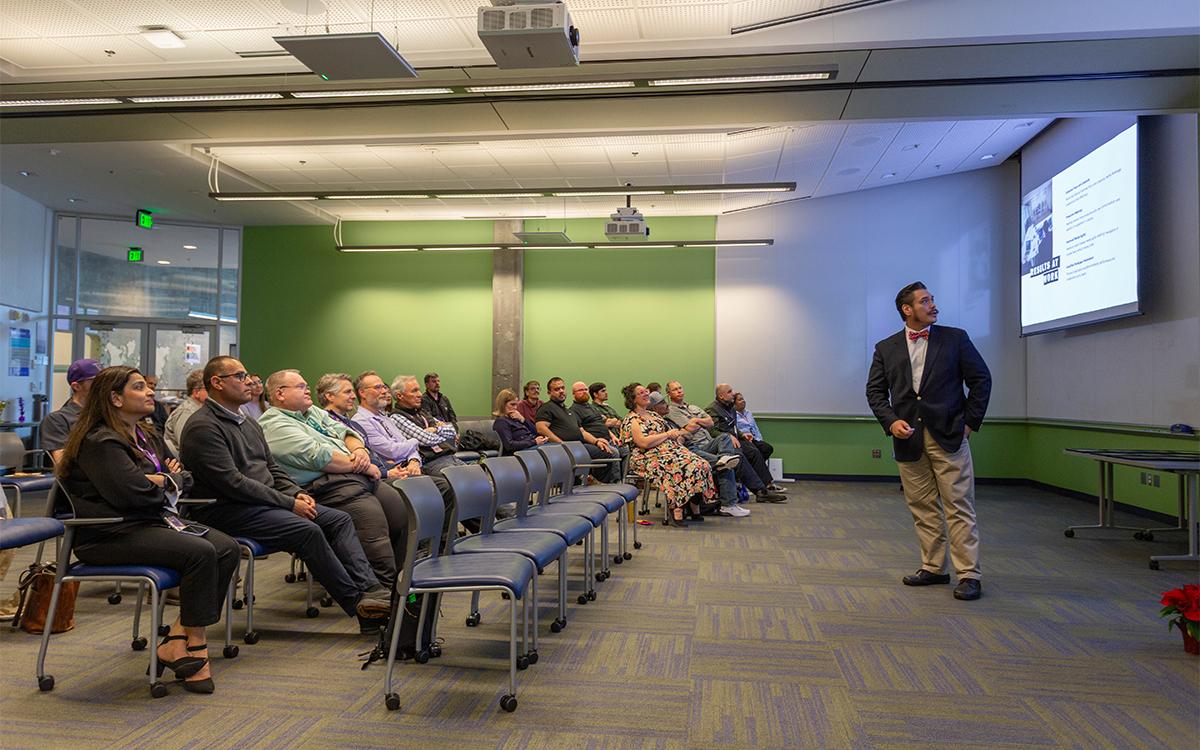 man in suit looks at slides while doing a presentation