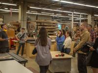 students gathered around a person giving a tour of the UW carpentry shop