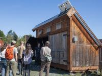 students gather around small building that slopes on one side