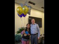 Interim Vice President of Facilities stands with Leula Amaha, who is holding balloons and flowers