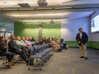 man in suit looks at slides while doing a presentation
