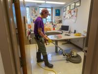 man using machine to strip wax from floor of office