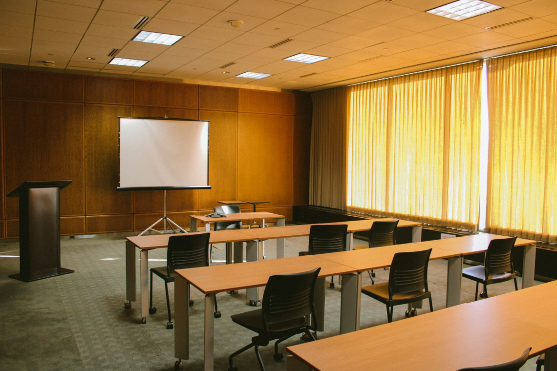 Magnolia Conference Room with shades drawn and projector screen and podium ready for a presenter