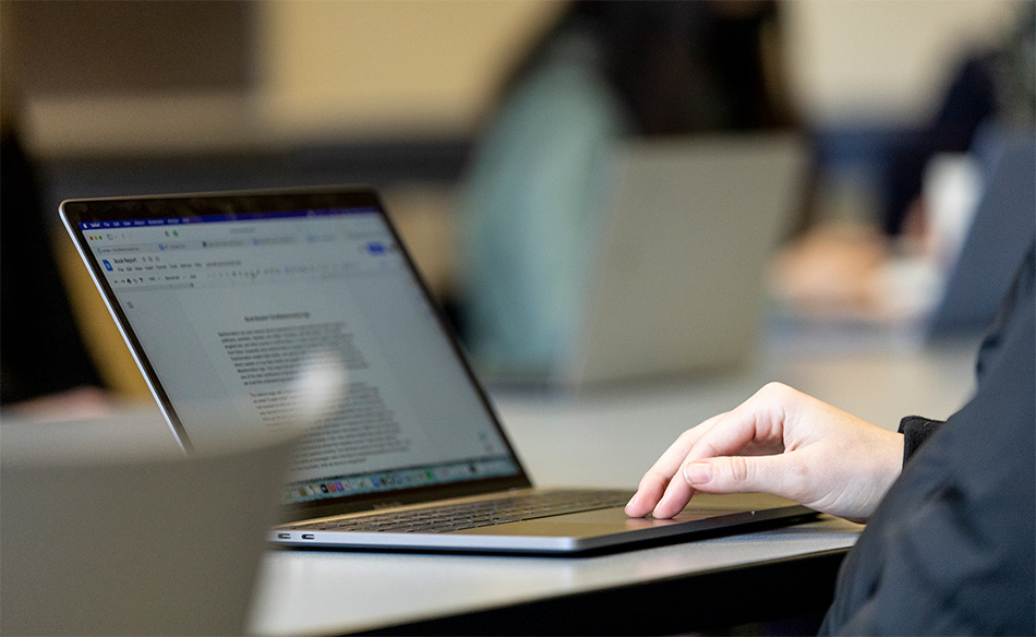 a person's hand on a Macbook looking at an essay on the screen