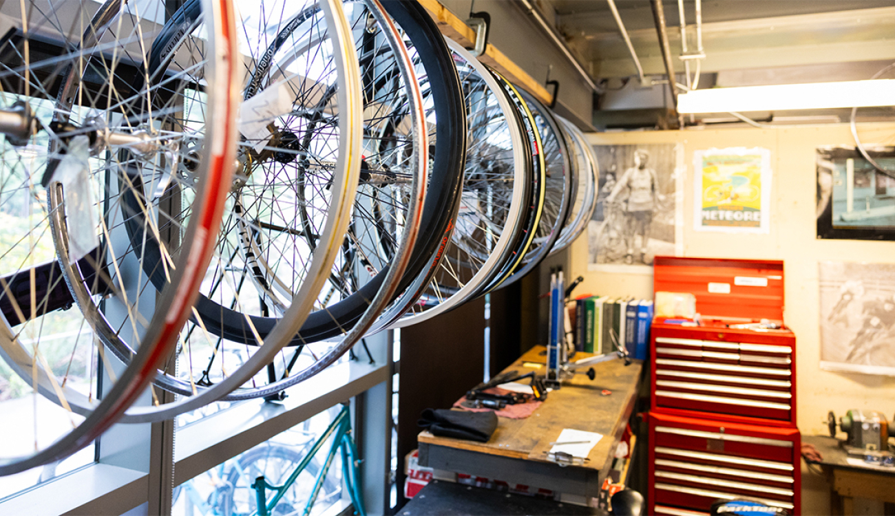 multiple bike wheels are on a wall with windows with a tool box in the back