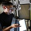 man using a laptop near lit up control panel