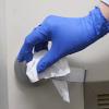 gloved hand of a custodian cleaning a door handle