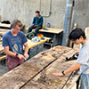 students working on big plank of wood in workshop