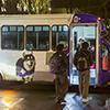 shuttle with a wrap that is purple and gold against nighttime background