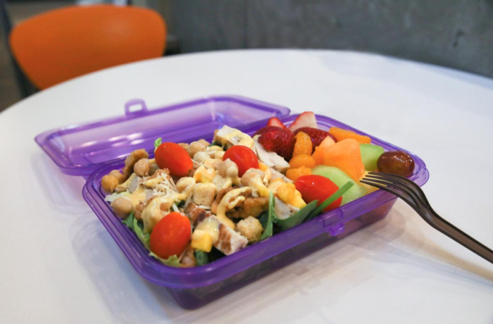 purple reusable container with a salad and fresh fruit inside