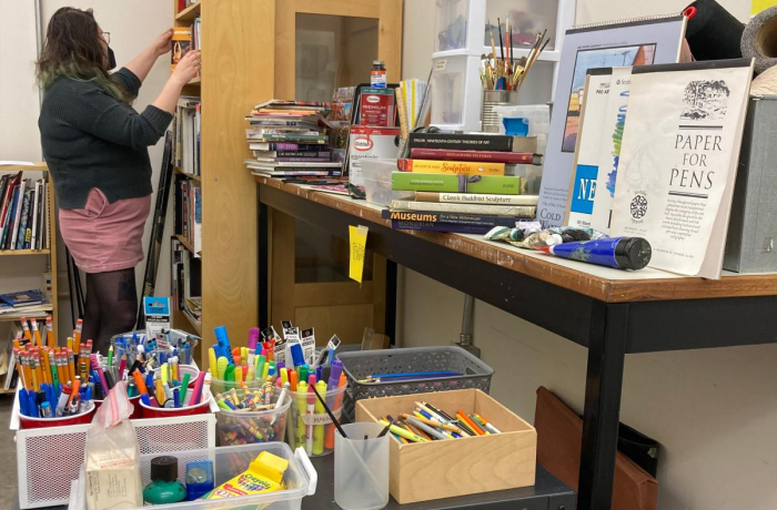 a person stacking books in the uw free materials library with a plethora of supplies and books shown