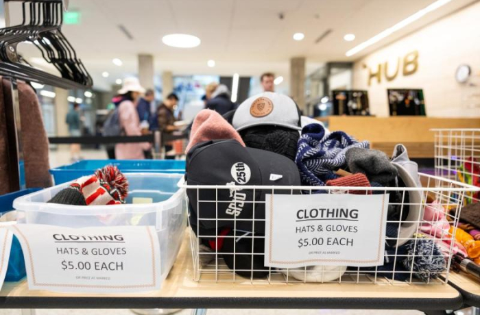 variety of clothing items in a basket on a desk next to some clothes hangers