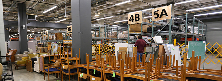 uw surplus store interior with stacked chairs in foreground and warehouse racks of items in background
