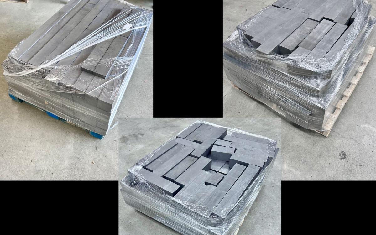 Three pallets full of black graphite blocks.