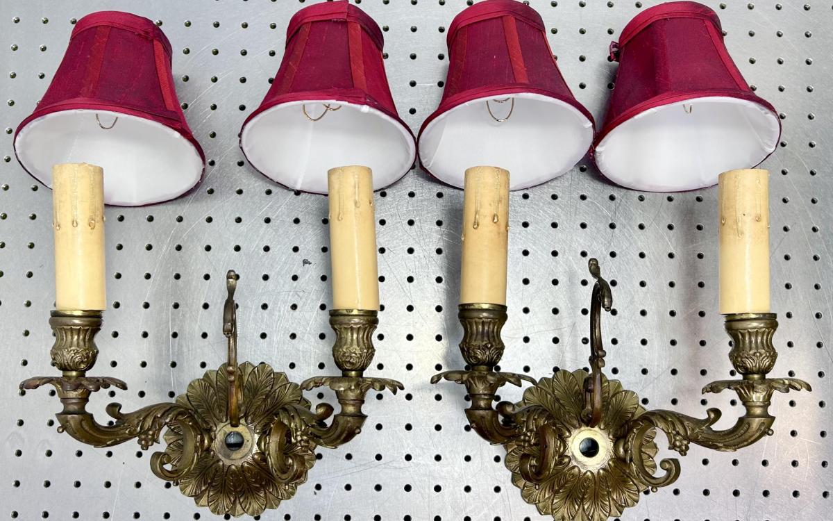 A pair of ornate wall sconces with red shades placed where they would sit on lightbulbs.