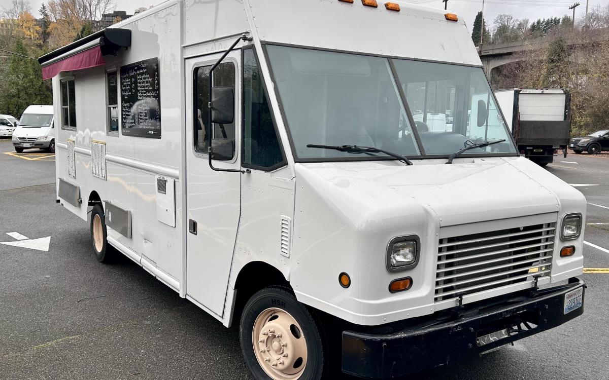 White food truck in a parking lot.
